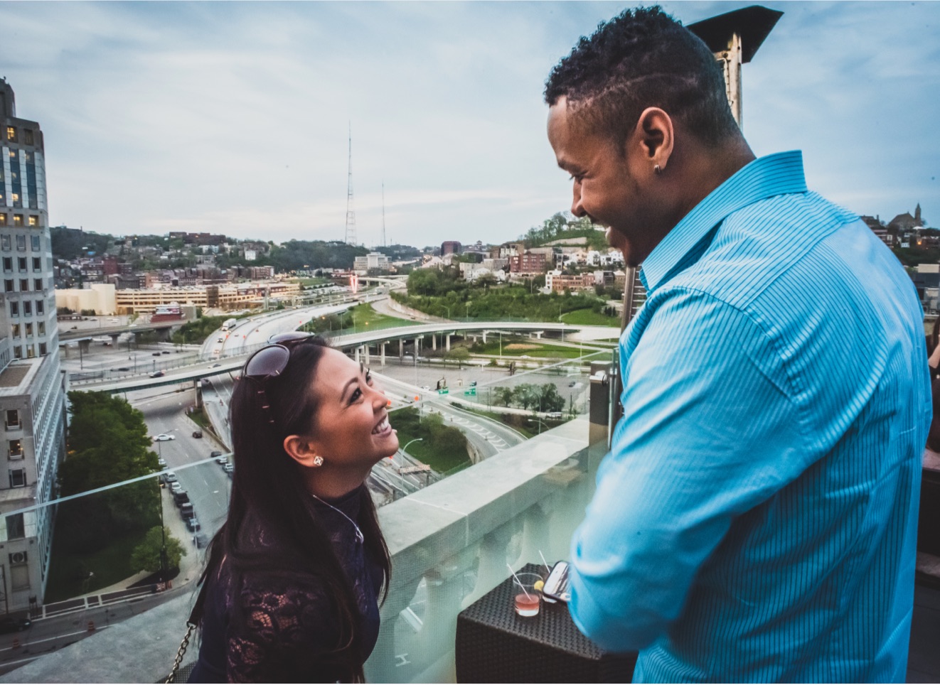 man and woman smiling at each other on a rooftop